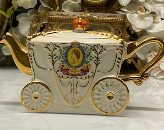 Tetera antigua con la imagen del carruaje real de la coronación de la reina Isabel. Caja de música.