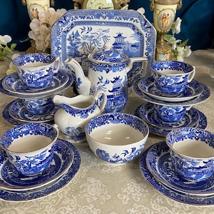 Könnte beinhalten: Eine Sammlung von blau-weißem Porzellan, darunter Teetassen, Untertassen, Schalen, eine Teekanne und ein Serviertablett. Das Set zeigt ein klassisches Willow-Muster. Die Tassen und Untertassen sind gestapelt, die Teekanne hat ein passendes Design.