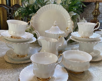 Può includere: Un set da tè bianco con finiture dorate. Il set comprende una teiera, un creamer, una zuccheriera e quattro tazze da tè e piattini.