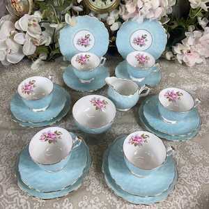 Könnte beinhalten: Ein Vintage-Tee-Set mit einem hellblauen und weißen Blumenmuster. Das Set enthält eine Teekanne, eine Milchkännchen, eine Zuckerdose, Tassen und Untertassen.