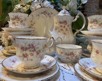 Peut inclure: Un service à thé floral vintage avec une théière, un sucrier, un pot à crème et des tasses et soucoupes. L'ensemble est décoré d'un motif floral délicat dans des tons de rose et de vert.
