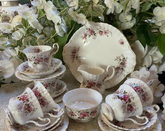May include: A vintage tea set with a floral pattern. The set includes a teapot, creamer, sugar bowl, and four teacups and saucers. The teacups and saucers have a delicate floral design with pink and green accents. The set is made of fine bone china and is in excellent condition.