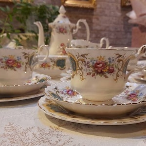 May include: A vintage tea set with floral patterns. The set includes a teapot, a sugar bowl, a creamer, and four teacups and saucers.