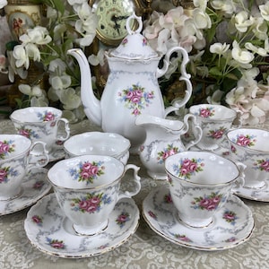 Puede incluir: Un juego de té blanco con diseños florales. El juego incluye una tetera, una jarra de crema, un azucarero y seis tazas de té y platillos.