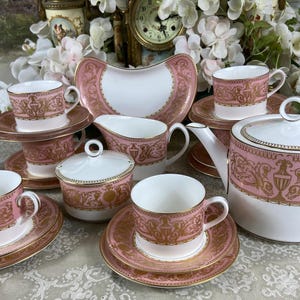 Puede incluir: Juego de té vintage rosa y dorado. El juego incluye tazas, platillos, tetera, cremera, azucarero y plato de servir. El juego de té tiene un estilo clásico y elegante.