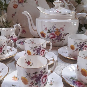 以下が含まれることがあります： ピンク、イエロー、ブルーの繊細な花柄が施された、ヴィンテージの花柄ティーセット。ティーポット、クリーマー、シュガーボウル、カップ＆ソーサー4客がセットになっています。