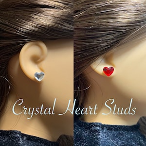 Peut inclure: Une paire de boucles d'oreilles clous en forme de cœur en cristal. Une boucle d'oreille est transparente et l'autre est rouge.