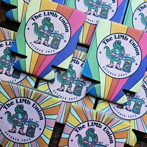 May include: A set of colorful can coolers featuring a cartoon alligator holding a chainsaw and the text "The Limb Union" with the date "October 2023".