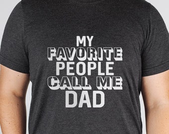 May include: A dark grey t-shirt with the text "MY FAVORITE PEOPLE CALL ME DAD" printed in white.