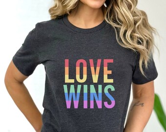 May include: A dark heather grey t-shirt with the text "LOVE WINS" printed in rainbow colors.