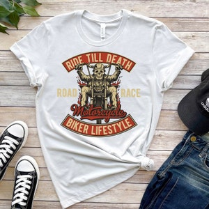 May include: White t-shirt with a graphic of a skeleton riding a motorcycle. The graphic includes the text "Ride Till Death", "Road", "Race", "Motorcycle", and "Biker Lifestyle".