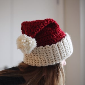 May include: A red and white crocheted Santa hat with a white pom-pom on top.