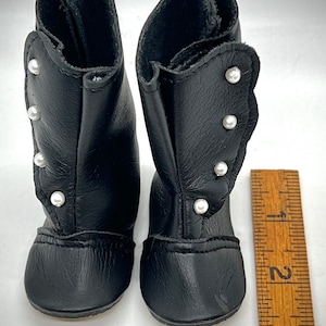 May include: A pair of black leather boots with pearl embellishments. The boots are about 2 inches tall and have a rounded toe.