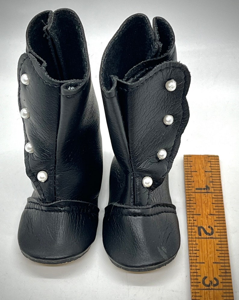 May include: A pair of black leather boots with pearl embellishments. The boots are about 2 inches tall and have a rounded toe.