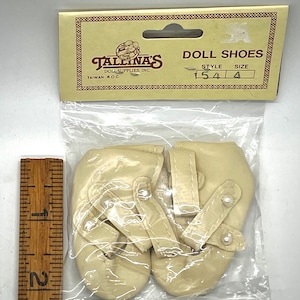 May include: A pair of white satin doll shoes with pearl accents. The shoes are packaged in a clear plastic bag with a label that reads "Tallina's Doll Supplies, Inc. Taiwan R.O.C." and "Doll Shoes Style 154 Size 4".