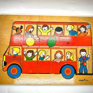 May include: A wooden double-decker bus puzzle with colorful characters and balloons. The bus is red with a white roof and black wheels. The characters are all smiling and have different colored clothes. The puzzle is made by Simplex Toys.