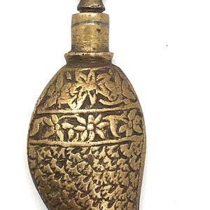 May include: A gold-colored metal bottle with a decorative fish-shaped body and a floral design on the top. The bottle has intricate details and a traditional design.
