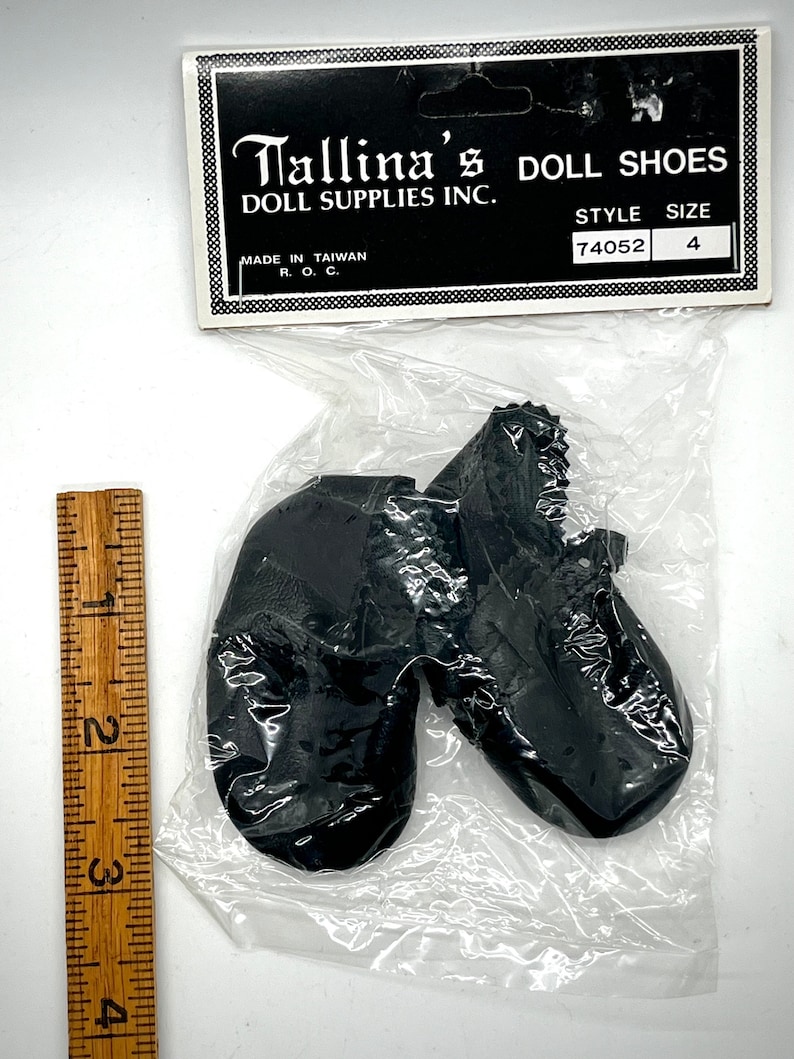 May include: A pair of black doll shoes in a plastic bag with a label that reads "Tallina's Doll Shoes Doll Supplies Inc. Style 74052 Size 4 Made in Taiwan R.O.C."