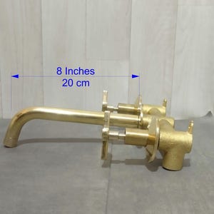 May include: Gold-toned bathroom faucet with two handles and a spout, measuring 8 inches or 20 cm in length.