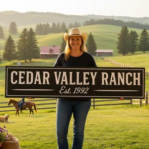 May include: A woman in a cowboy hat holds a black sign that reads "CEDAR VALLEY RANCH Est. 1992" in white lettering. The sign is set against a backdrop of a green pasture, trees, and a blue sky.