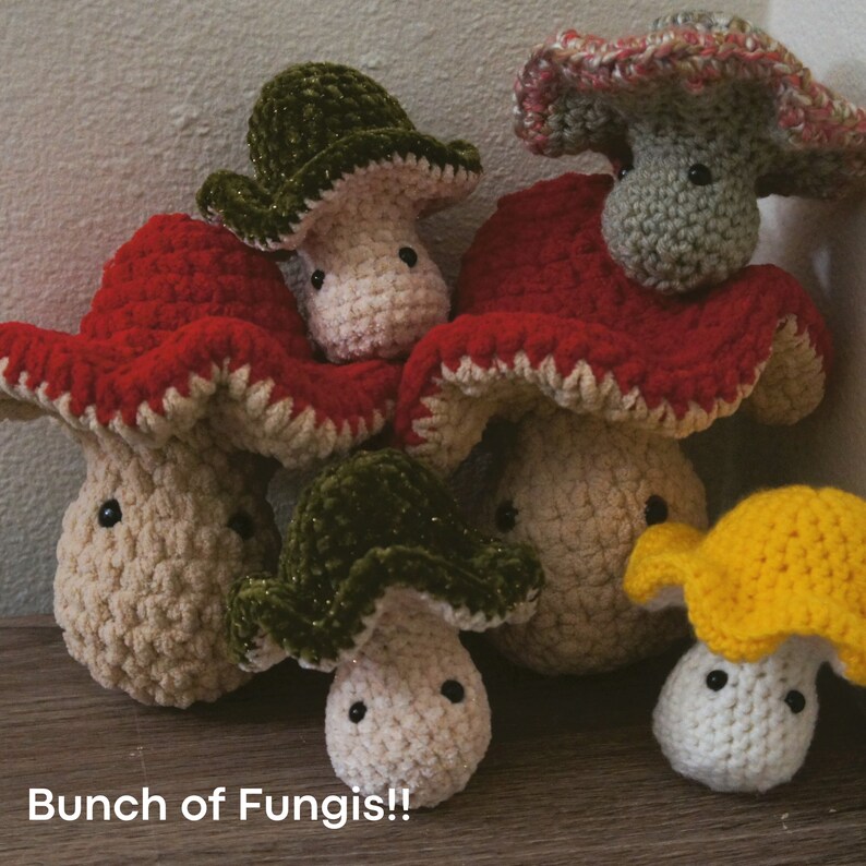 May include: A group of crocheted mushroom plushies in various colors, including red, green, yellow, and white. The mushrooms have different colored caps and are arranged in a cluster.