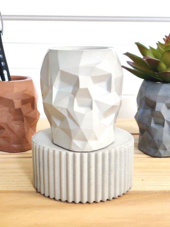 A hand-cast geometric skull concrete planter — edgy desk decor that doubles as a functional pot for succulents or air plants, with genuine gothic visual punch.