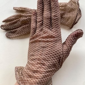May include: A pair of brown gloves featuring a fine, repeating diamond mesh pattern throughout the fabric. The gloves have a scalloped edge at the wrist opening and are constructed from a lightweight, semi-sheer material with a textured finish.