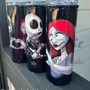 Puede incluir: Cuatro vasos de acero inoxidable negros con personajes de The Nightmare Before Christmas. Cada vaso tiene una banda de pedrer&iacute;a negra en la parte superior y un dise&ntilde;o de Jack Skellington y Sally. El texto en la parte inferior dice "Tumblers stainless/ Vasos T&eacute;rmicos."