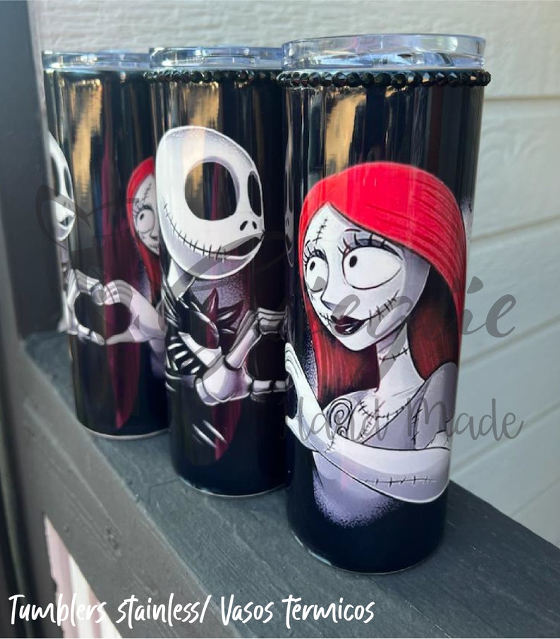 Puede incluir: Cuatro vasos de acero inoxidable negros con personajes de The Nightmare Before Christmas. Cada vaso tiene una banda de pedrer&iacute;a negra en la parte superior y un dise&ntilde;o de Jack Skellington y Sally. El texto en la parte inferior dice "Tumblers stainless/ Vasos T&eacute;rmicos."