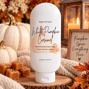 May include: A white squeeze bottle of body butter cream labelled White Pumpkin Caramel by Megans Gift Haven. The label features a pumpkin illustration, caramel cubes, and states a net weight of 227 grams or 8 ounces for feet, hands, and body.