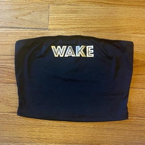 May include: A black tube top with the word "WAKE" printed in silver on the front.