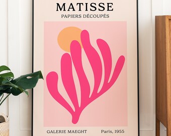Op de afbeelding: Een zwart ingelijste poster met een roze achtergrond en een roze abstract ontwerp. De poster luidt "MATISSE PAPIERS DÉCOUPÉS GALERIE MAECHT Paris, 1955".