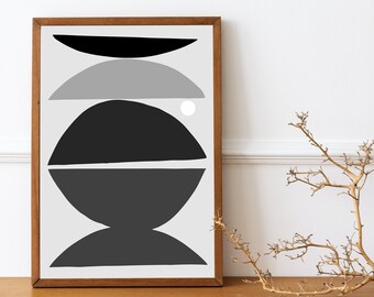 Puede incluir: Impresión artística abstracta en un marco de madera. La obra presenta un diseño minimalista con formas negras, grises y blancas. Las formas incluyen semicírculos y un círculo, creando una composición equilibrada. La impresión se muestra en un mueble de madera.