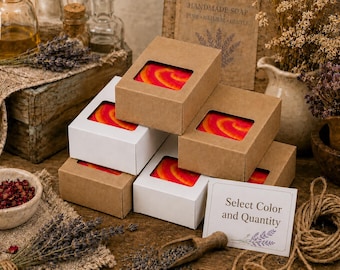 May include: A stack of rectangular soap boxes with clear windows, revealing bars with a vibrant red and orange swirl pattern. The boxes are made of brown kraft paper and white cardstock. A small white card with the text Select Color and Quantity.