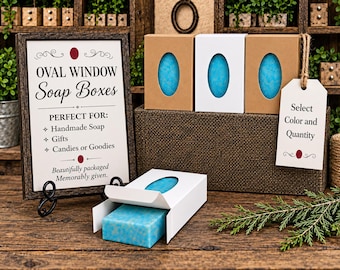 May include: Rectangular soap boxes featuring an oval window cutout, showcasing bright blue soap bars. The set includes brown and white cardboard boxes, a framed sign reading OVAL WINDOW Soap Boxes, and a hanging tag labeled Select Color and Quantity.