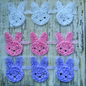 May include: Nine fabric bunny shapes, each made of rosettes. Three are white, three are pink, and three are purple.