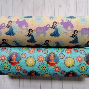 Peut inclure: Deux rouleaux de tissu avec un motif répété d'un personnage de princesse du film Aladdin. Le rouleau du haut a un fond jaune clair avec des éléphants violets et un génie. Le rouleau du bas a un fond turquoise avec un motif floral répété et le personnage de la princesse.