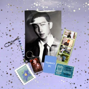 May include: A collection of fan merchandise featuring a black and white portrait, a keychain, a photo strip, a sticker, and a mystery PC card. The keychain has a photo of a person. The sticker has a blue flower and the word "NAMJOON".