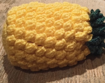 May include: A crocheted pineapple-shaped toy with a yellow body and green leaves.