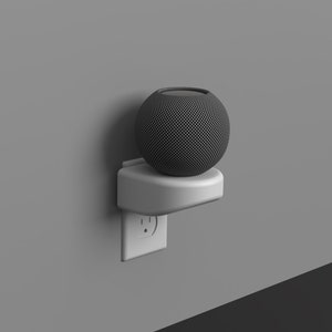 May include: A white wall mount outlet adapter with a black spherical smart speaker on top. The speaker has a textured surface.