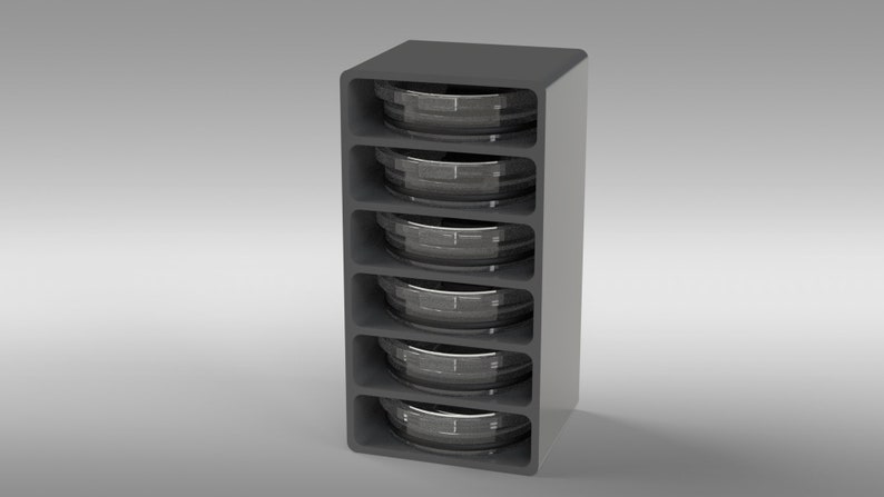 May include: A gray, vertical storage unit with five compartments, each holding a circular, metallic object. The unit has a rounded top and a smooth, modern design. The objects appear to be containers or components.