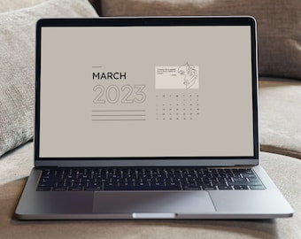 May include: A laptop computer on a beige sofa with a calendar for March 2023 displayed on the screen. The calendar has a line drawing of a face.