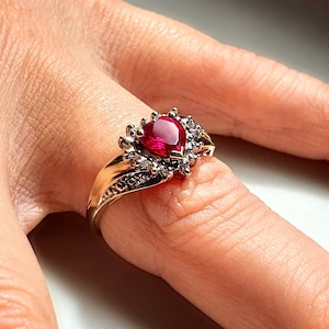 Op de afbeelding: Een gouden ring met een grote peervormige robijn, omringd door kleinere diamanten.