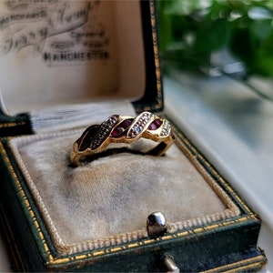 May include: A gold ring with red and white stones set in a twisted band. The ring is in a green velvet ring box.