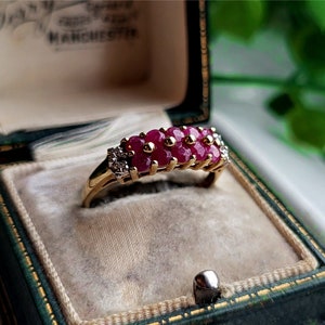 Op de afbeelding: Een gouden ring met een rij robijnen en een rij kleinere diamanten.