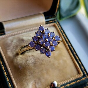 May include: A gold ring with a cluster of purple gemstones set in a flower shape.