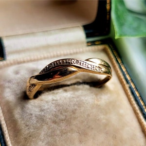 K&ouml;nnte beinhalten: Ein Goldring mit einem gedrehten Design und kleinen Diamanten, die in die Band eingefasst sind.