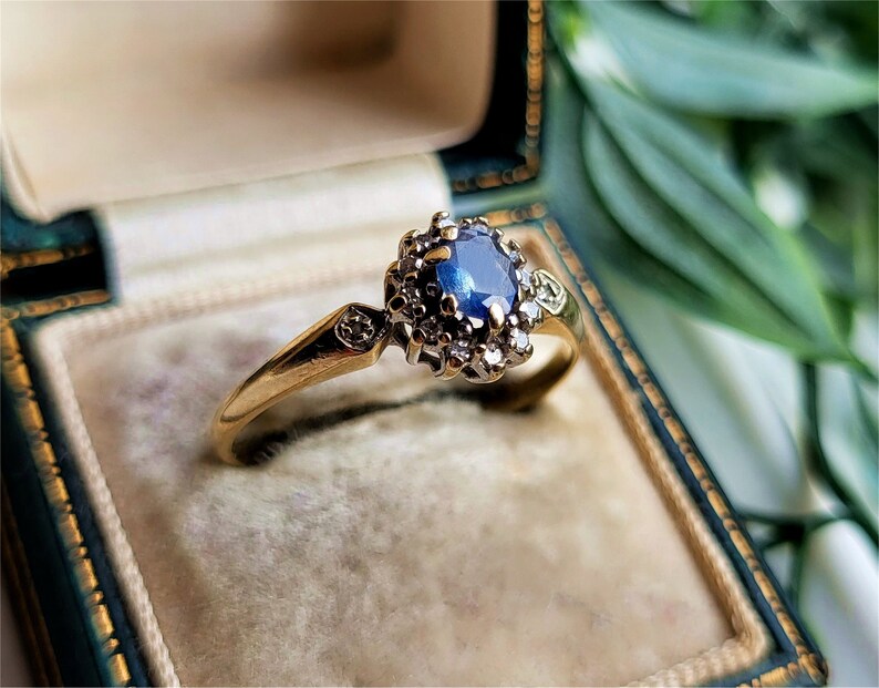 Pode incluir: Um anel de ouro com um safira azul cercado por uma halo de pequenos diamantes.