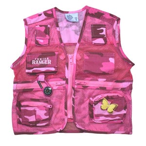May include: Pink camouflage vest with multiple pockets, a zipper closure, and a compass attached to the front. The vest has a patch that says "Junior Ranger" on the front.