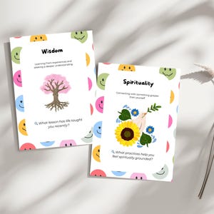 May include: Two white cards with colourful smiley face borders. One card says "Wisdom" with a pink tree illustration. The other says "Spirituality" with a sunflower and dove illustration. Each card has a question.